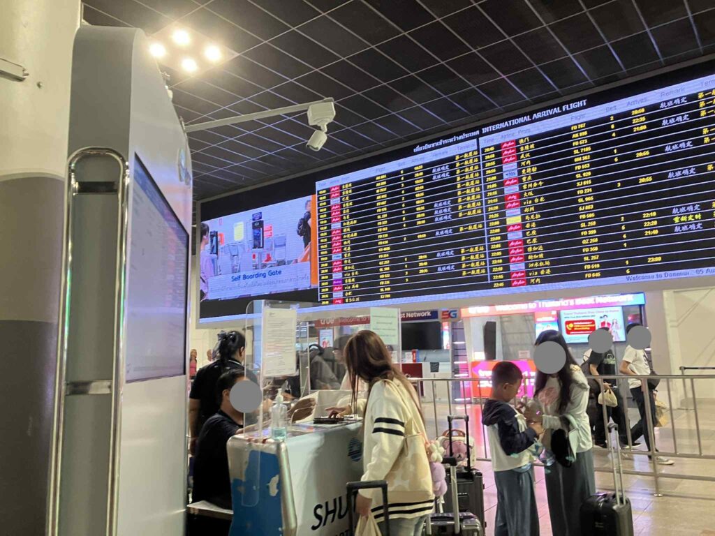 Shuttle bus registration counter near the international arrival flight board at Don Mueang Airport